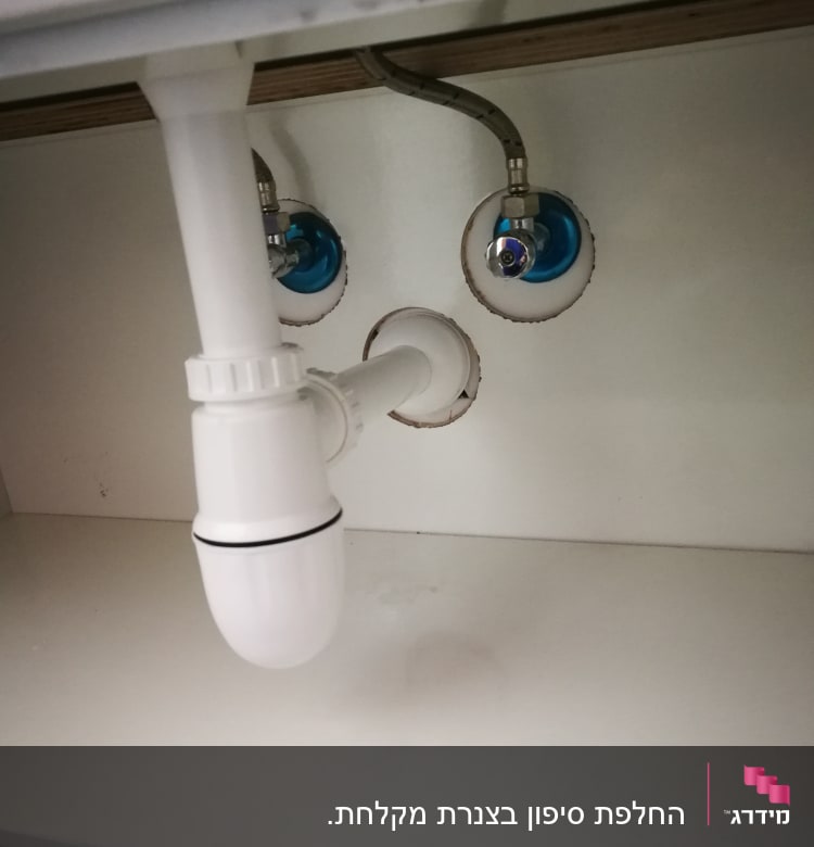 צינור ניקוז לבן מתחת לכיור עם חיבורים